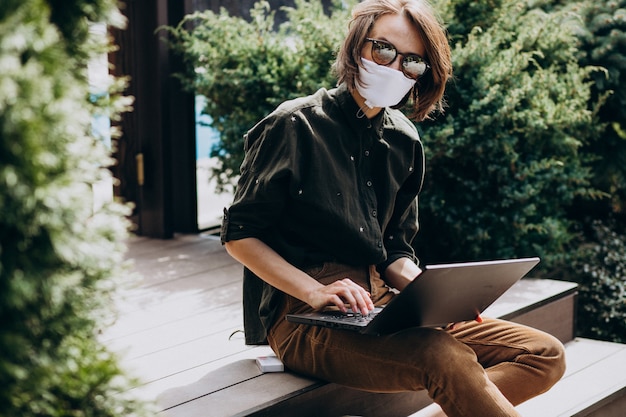 Mujer de negocios joven trabajando en la computadora desde su casa en la máscara