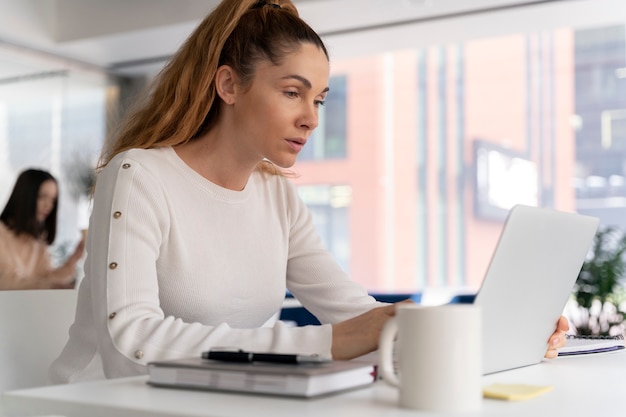 Mujer de negocios joven en el trabajo en la oficina con ordenador portátil