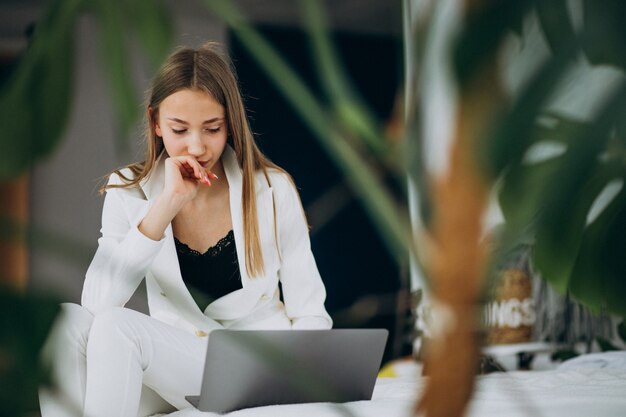 Mujer de negocios joven en traje blanco trabajando en una computadora