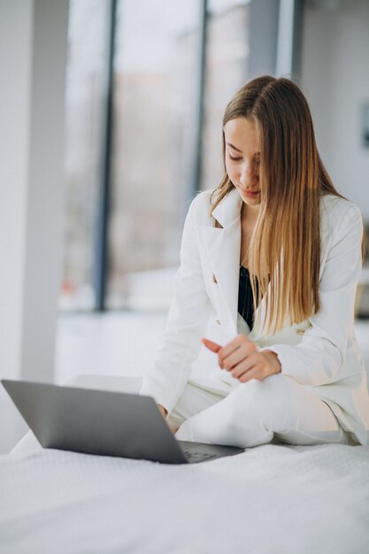 Mujer de negocios joven en traje blanco trabajando en una computadora