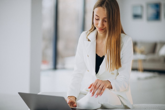 Mujer de negocios joven en traje blanco trabajando en una computadora