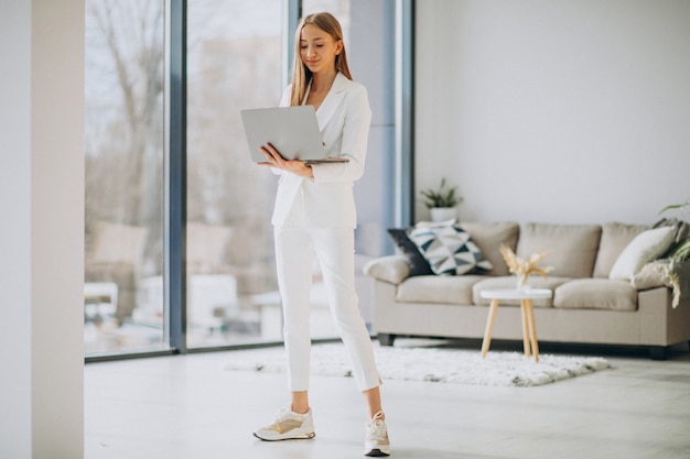 Mujer de negocios joven en traje blanco trabajando en una computadora