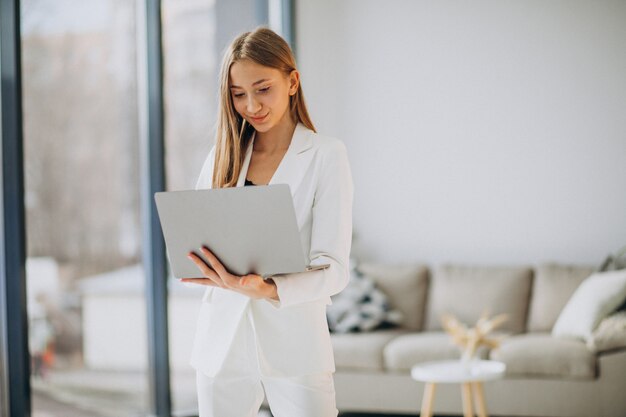 Mujer de negocios joven en traje blanco trabajando en una computadora