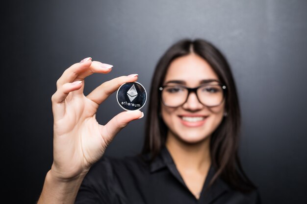 Mujer de negocios joven en vasos con Litecoin en manos aisladas sobre pared negra.