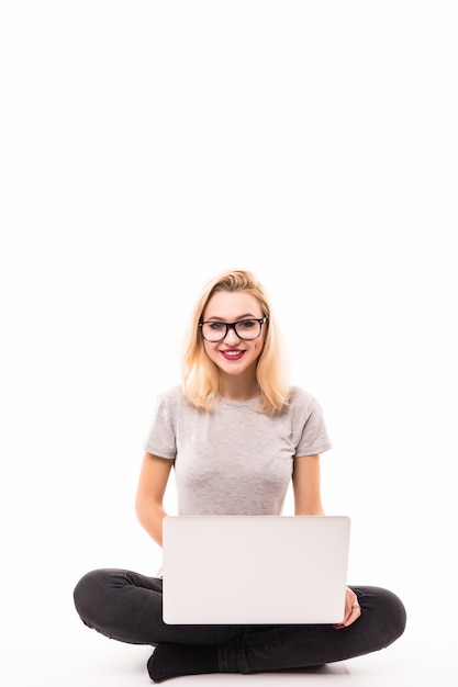 Mujer de negocios con laptop en jeans negros está sentada en el piso