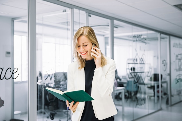 Mujer de negocios llamando y mirando en libro