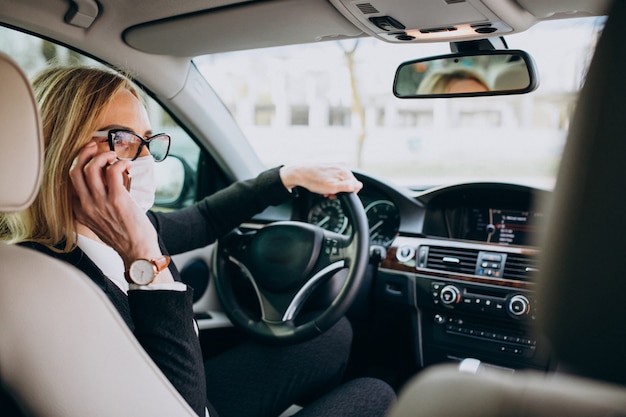 Mujer de negocios con máscara de protección sentado dentro de un automóvil