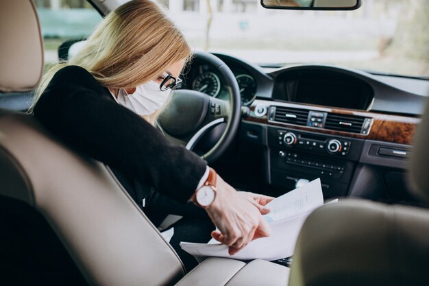 Mujer de negocios con máscara de protección sentado dentro de un automóvil