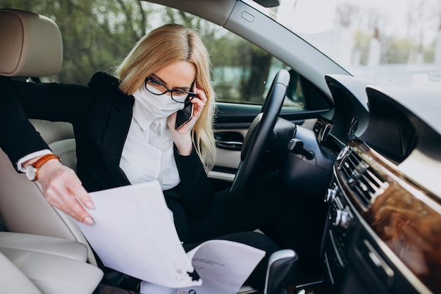 Mujer de negocios con máscara de protección sentado dentro de un automóvil