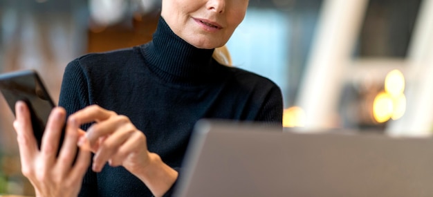 Mujer de negocios mayor que trabaja en la computadora portátil y el teléfono inteligente