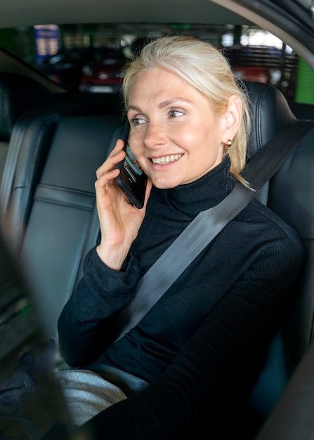 Mujer de negocios mayor sonriente en una llamada telefónica en coche