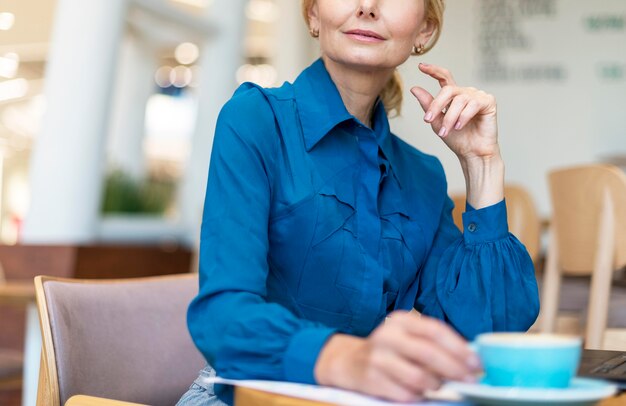 Mujer de negocios mayor tomando café mientras trabaja