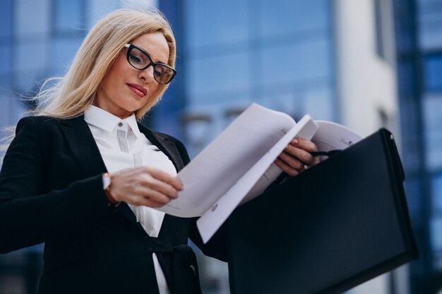 Mujer de negocios de mediana edad con documentos por el centro de negocios