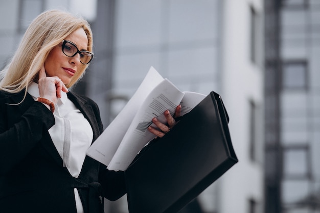 Mujer de negocios de mediana edad con documentos por el centro de negocios