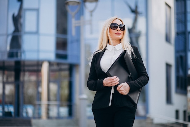 Mujer de negocios de mediana edad con maleta por centro de negocios