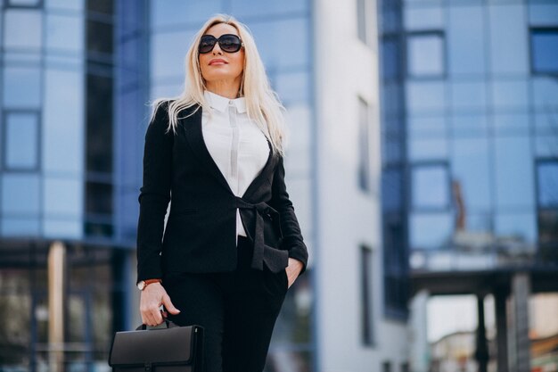 Mujer de negocios de mediana edad con maleta por centro de negocios