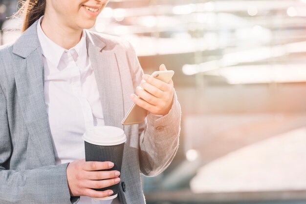 Mujer de negocios mirando a smartphone al aire libre