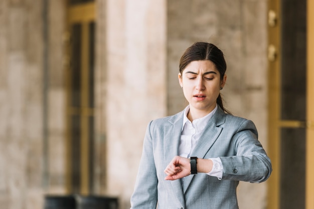 Mujer de negocios moderna mirando a reloj al aire libre