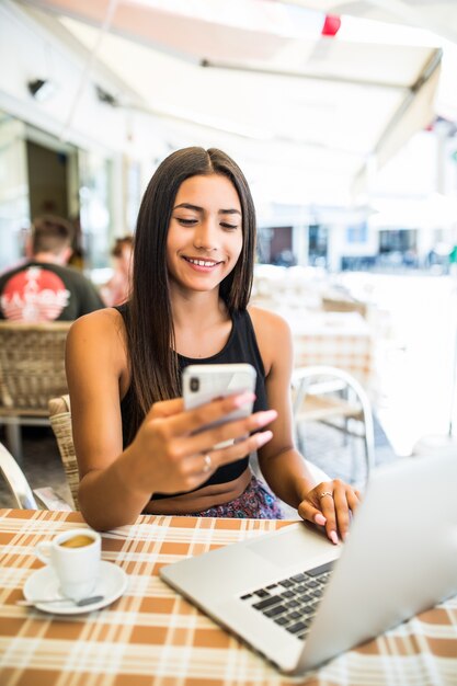 Mujer de negocios moderna o trabajo exitoso en teléfono inteligente y computadora portátil en el interior de la cafetería, estudiante sentada en la biblioteca de la universidad mientras usa tecnología, trabajo a distancia de internet