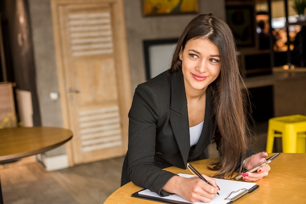 Mujer de negocios morena escribiendo en un documento