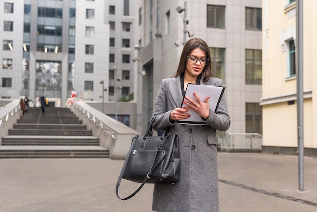 Mujer de negocios morena leyendo documento en el exterior