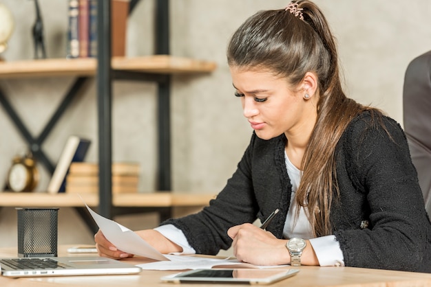 Mujer de negocios morena leyendo en su oficina