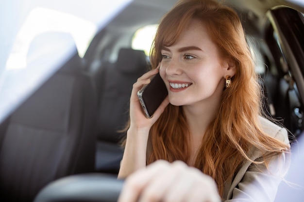 Mujer de negocios multitarea mientras conduce hablando por teléfono Mujer sonriente hablando por teléfono mientras conduce Mujer hablando por móvil mientras conduce