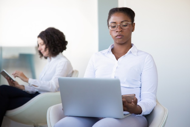 Mujer de negocios con ordenador portátil y teléfono inteligente