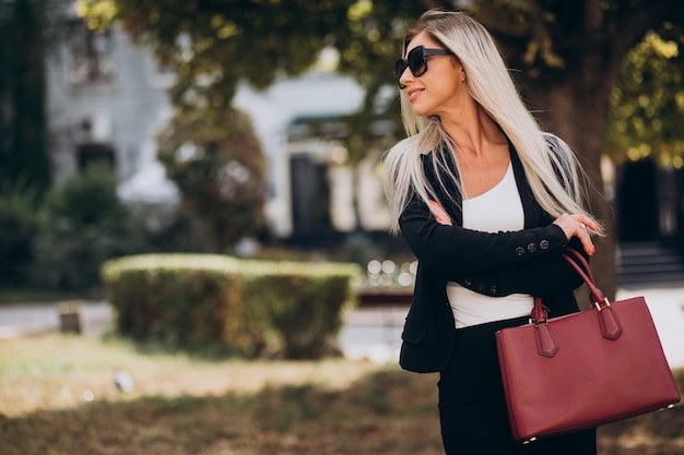 Foto gratuita mujer de negocios en el parque con bolsa roja