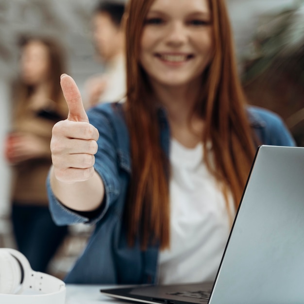 Foto gratuita mujer de negocios pelirroja sonriente dando un pulgar hacia arriba