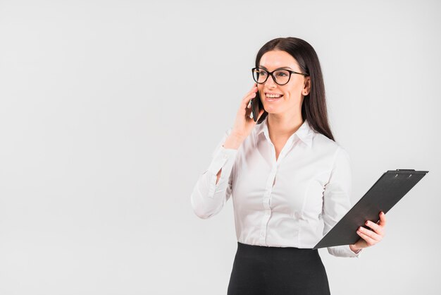 Mujer de negocios con portapapeles hablando por teléfono