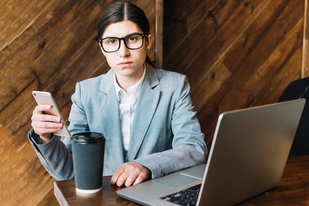 Mujer de negocios con portátil y smartphone en cafetería