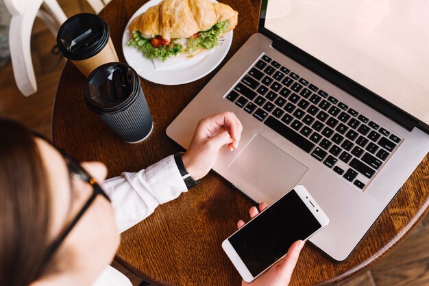 Mujer de negocios con portátil y smartphone en cafetería