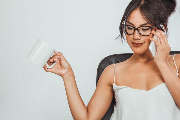 Mujer de negocios posando con taza de café y teléfono