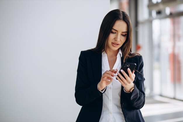 mujer de negocios, posición, en, oficina, y, utilizar, teléfono móvil