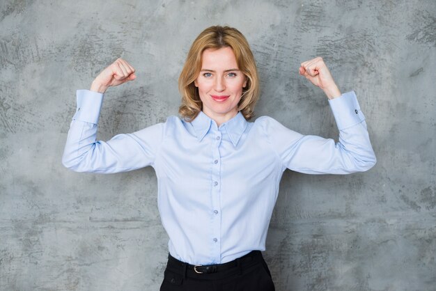 Mujer de negocios que muestra los músculos del brazo