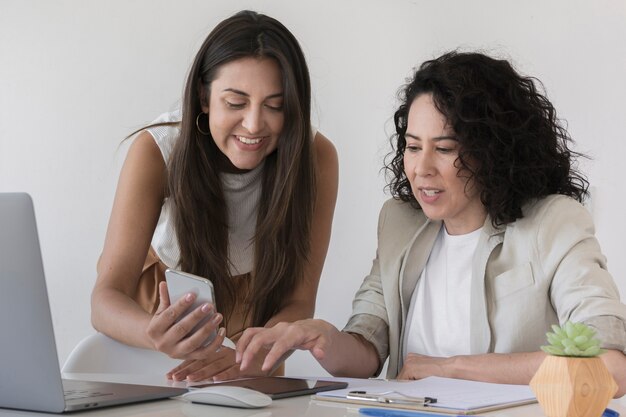 Mujer de negocios que muestra a su colega algo en el teléfono