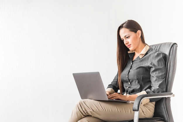 Mujer de negocios que permanece en su computadora portátil con el espacio de la copia