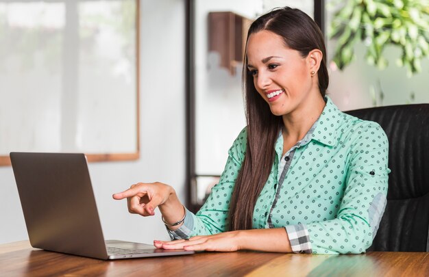 Mujer de negocios que señala en la computadora portátil