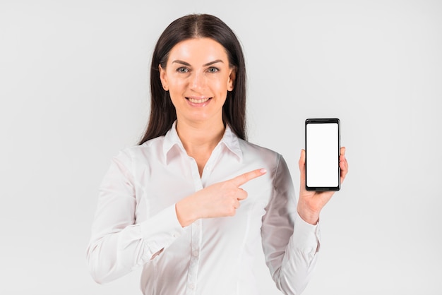 Mujer de negocios que señala el dedo en el teléfono inteligente con pantalla en blanco