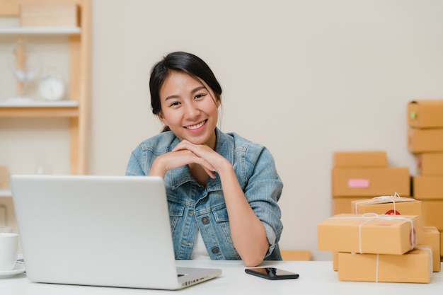 Mujer de negocios que siente la sonrisa feliz y que mira a la cámara mientras que trabaja en su oficina en casa.