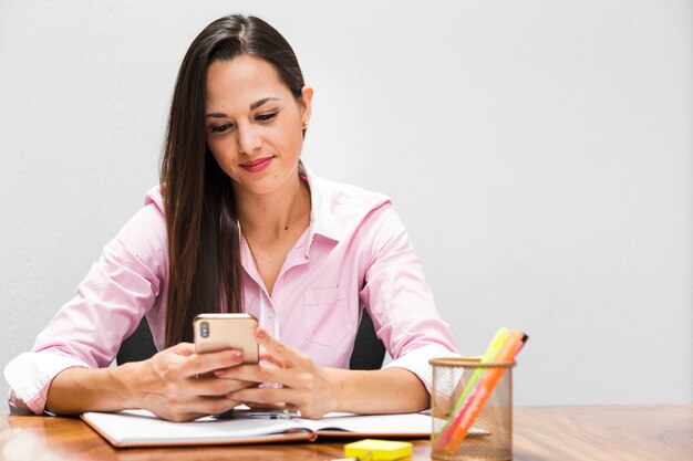 Mujer de negocios que sonríe y que controla su teléfono