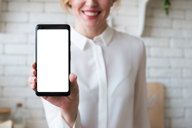 Mujer de negocios que sostiene smartphone con la pantalla en blanco