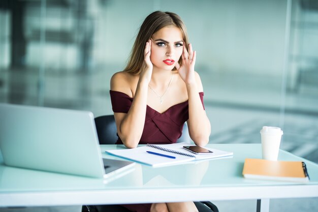 Mujer de negocios que sufre dolor de cabeza en el trabajo usando una computadora de escritorio en la oficina