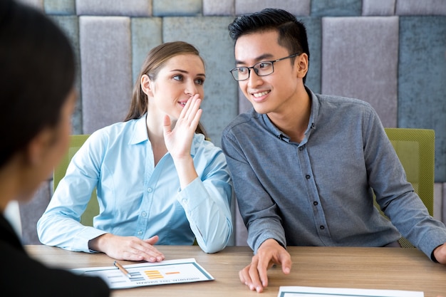 Mujer de negocios que susurra secreto al colega masculino