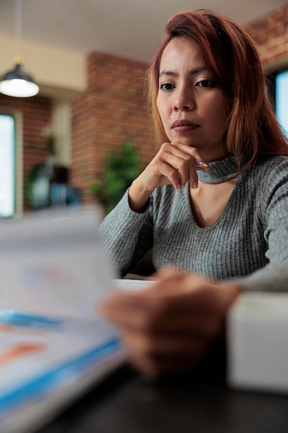 Foto gratuita mujer de negocios que tiene documentos de la empresa que verifican las estadísticas de marketing mientras trabaja en la estrategia de asociación en la oficina de inicio. gerente ejecutivo lluvia de ideas para el proyecto empresarial