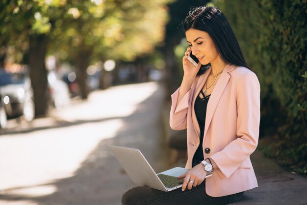 Mujer de negocios que trabaja en la computadora portátil afuera