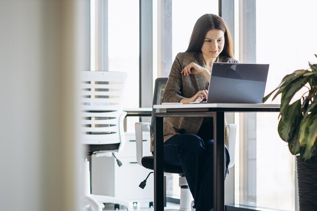 Mujer de negocios que trabaja en la computadora portátil en la oficina