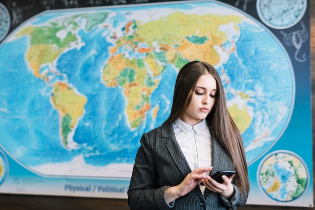 Mujer de negocios que usa teléfono inteligente en la oficina