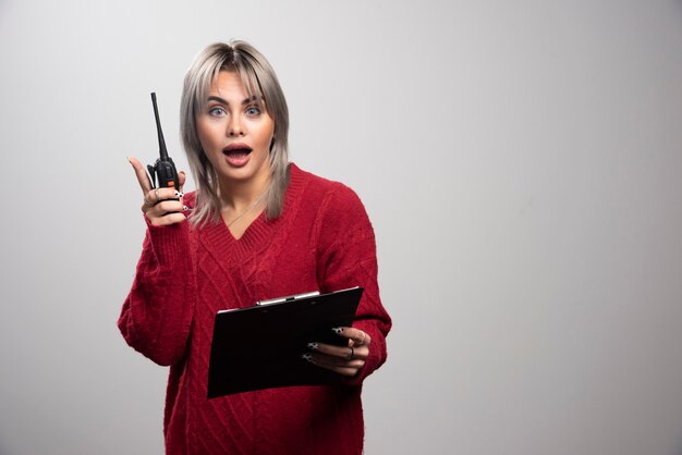 Mujer de negocios recibiendo una sacudida eléctrica sobre fondo gris.